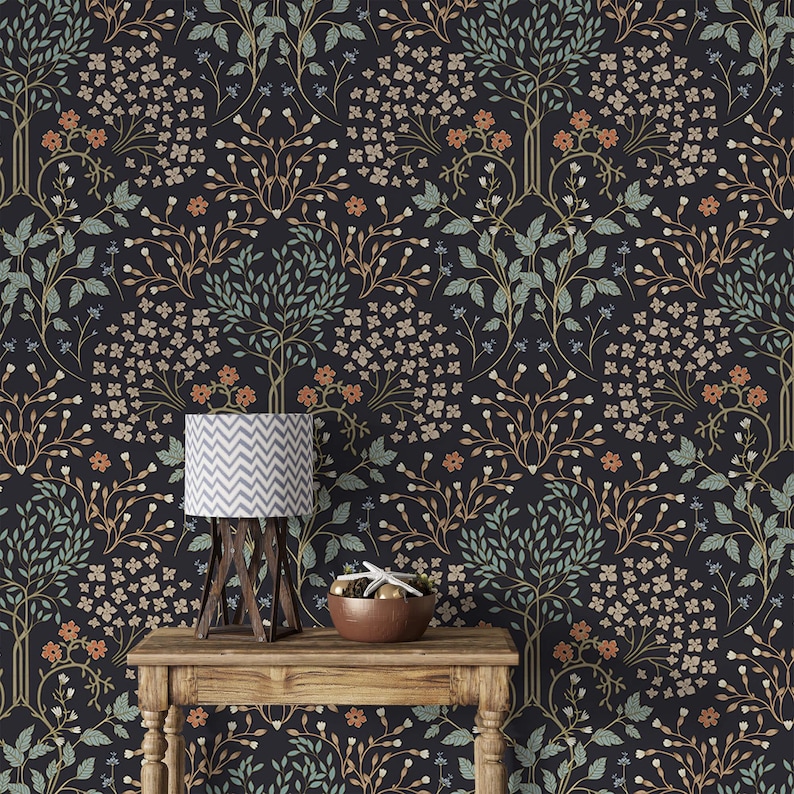 May include: A dark blue wallpaper with a repeating pattern of stylized trees and flowers in shades of green, orange, and white. A table with a lamp and a bowl sits in front of the wallpaper.