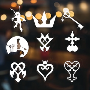 May include: A collection of white die-cut vinyl stickers featuring various Kingdom Hearts symbols. Includes a crown, keyblade, heart, and character silhouettes. The stickers are displayed against a blurred background.