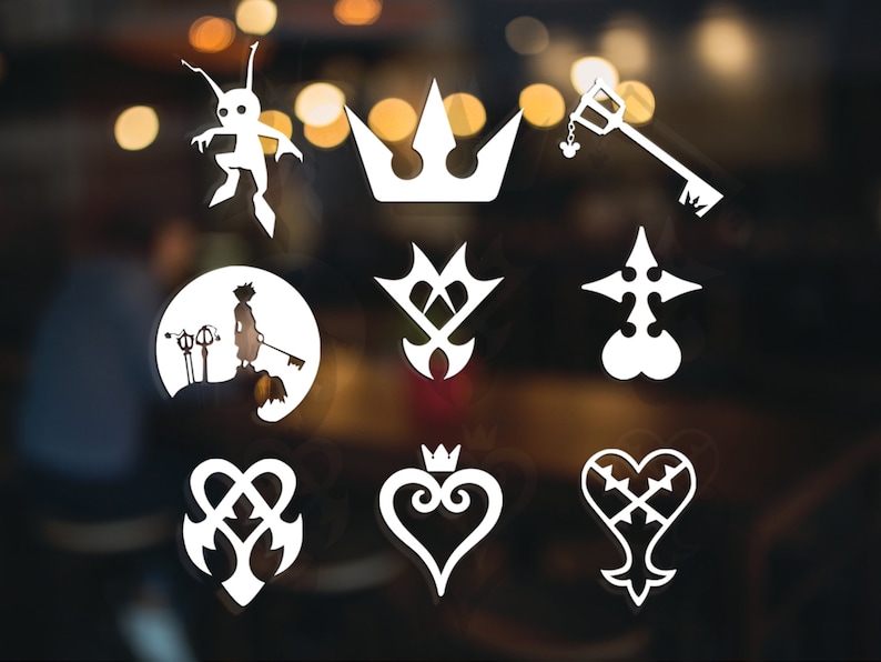 May include: A collection of white die-cut vinyl stickers featuring various Kingdom Hearts symbols. Includes a crown, keyblade, heart, and character silhouettes. The stickers are displayed against a blurred background.