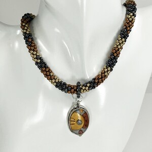 Beaded necklace. Tiny Gold, Silver, and Copper Czech glass beads in the Bead Crochet technique with a Poly and Silver Pendant.