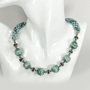 Beaded necklace. Hand made green ceramic beads plus tiny Czech glass beads in the bead crochet technique. Black and silver accents.