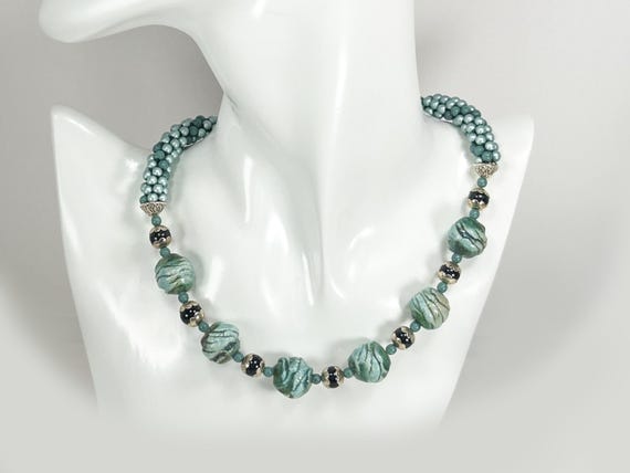 Beaded necklace. Hand made green ceramic beads plus tiny Czech glass beads in the bead crochet technique. Black and silver accents.