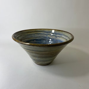 May include: A brown and blue ceramic bowl with a swirling pattern. The bowl is wide at the top and narrows to a point at the bottom.