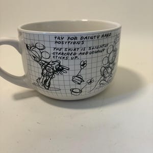 Puede incluir: Taza de cer&aacute;mica blanca con una ilustraci&oacute;n de dibujos animados en blanco y negro y texto. La taza tiene un asa y un patr&oacute;n de cuadr&iacute;cula. El texto en la taza dice: "TRY FOR DAINTY HAND POSITIONS. THE SKIRT IS SLIGHTLY STARCHED AND USUALLY STICKS UP."