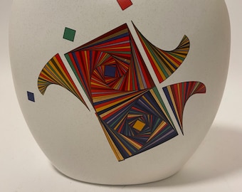 May include: White ceramic vase with a geometric design in shades of red, yellow, green, blue, and brown. The design features a swirling pattern of lines and squares.
