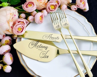 Könnte beinhalten: Goldenes Hochzeitstortenmesser- und -server-Set mit den Namen Melany und Leo und dem Datum 07.12.25, das in die Griffe graviert ist. Das Set befindet sich auf einem weißen Teller mit goldenem Rand.