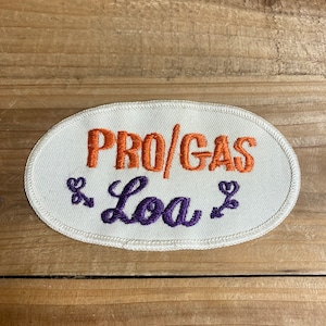 May include: White oval embroidered patch with the text "PRO/GAS & Loa" in orange and purple thread.