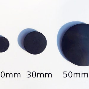 Puede incluir: Tres discos redondos negros de diferentes tamaños, que miden aproximadamente 20 mm, 30 mm y 50 mm de diámetro.