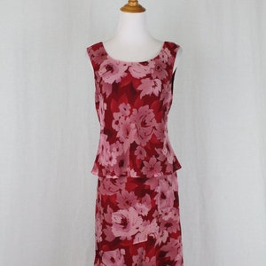 May include: A sleeveless, red and pink floral print dress with a tiered skirt. The dress has a scoop neck and a fitted bodice.