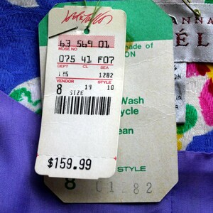 May include: A white, blue, green, and yellow floral fabric with a purple fabric underneath. A white tag with black text reads "63 569 01 MDSE NO 075 41 F07 DEPT CL SEA 125 1282 VENDOR STYLE 8 19 10 SIZE" and a barcode. The tag also has a price tag that reads "$159.99". A green tag with white text reads "made of ON Nash ycle ean STYLE 01282". A white tag with black text reads "ANNA &Eacute;L".