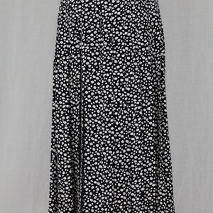 May include: A black and white pleated skirt with a polka dot pattern. The skirt is knee-length and has a fitted waist.