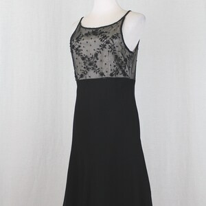 Pode incluir: Um vestido preto sem mangas com um corpete de renda transparente com um padr&atilde;o floral. A saia &eacute; de linha A e chega aos joelhos.