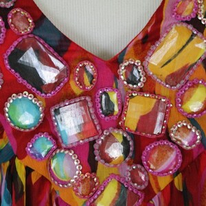 May include: A red, orange and blue patterned dress with a V-neckline and embellished with colourful rhinestones.