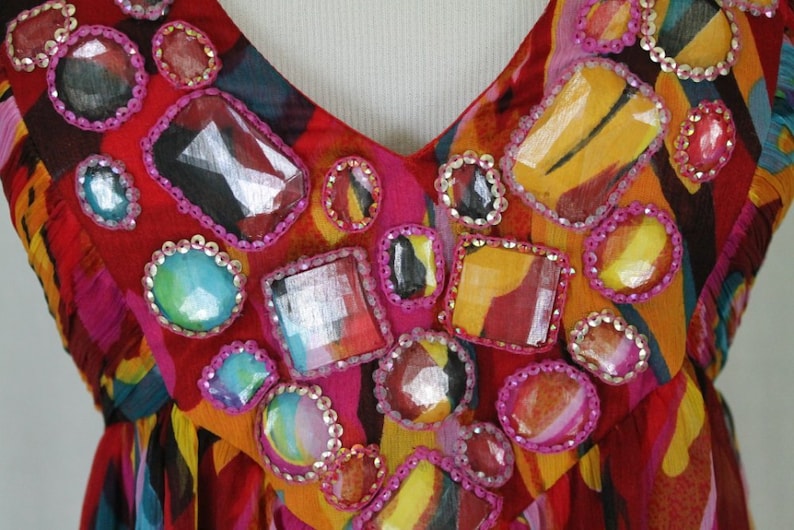 May include: A red, orange and blue patterned dress with a V-neckline and embellished with colourful rhinestones.