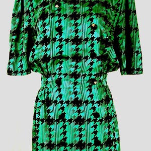 May include: A green and black dress with a houndstooth pattern. The dress has a short sleeve and a fitted silhouette.
