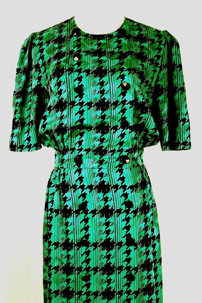 May include: A green and black dress with a houndstooth pattern. The dress has a short sleeve and a fitted silhouette.