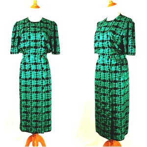 May include: A green and black houndstooth print dress with a matching jacket. The dress has a fitted bodice and a skirt that falls to the knees. The jacket has short sleeves and a button closure.
