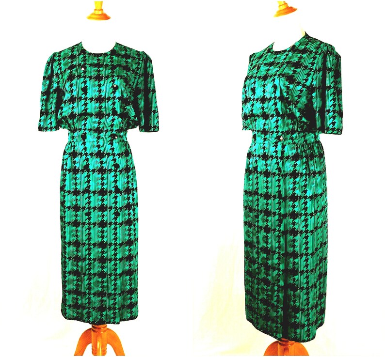 May include: A green and black houndstooth print dress with a matching jacket. The dress has a fitted bodice and a skirt that falls to the knees. The jacket has short sleeves and a button closure.