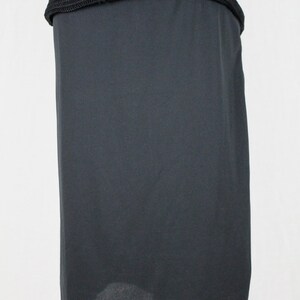 May include: A black skirt made of a smooth, silky fabric. The skirt is knee-length and has a straight silhouette.