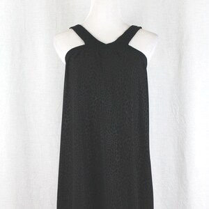 May include: A black sleeveless dress with a geometric pattern. The dress has a halter neckline and a loose fit.