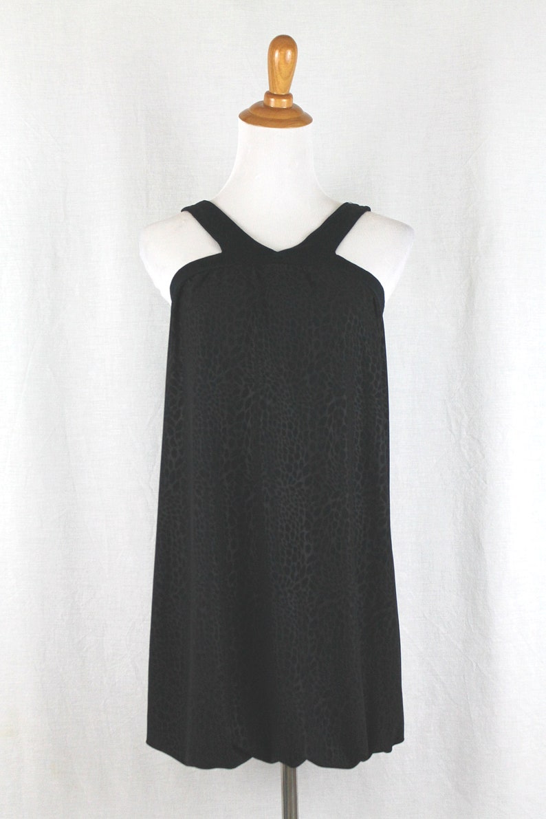 May include: A black sleeveless dress with a geometric pattern. The dress has a halter neckline and a loose fit.