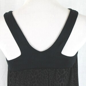 May include: Black sleeveless dress with a black v-neck and a black and white animal print skirt.