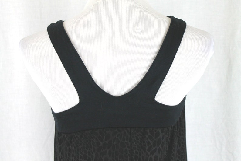 May include: Black sleeveless dress with a black v-neck and a black and white animal print skirt.