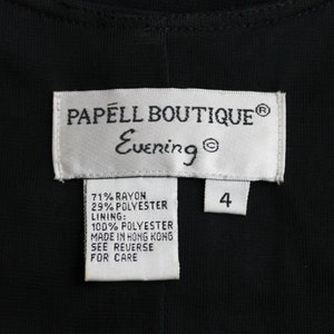 K&ouml;nnte beinhalten: Ein wei&szlig;es Etikett mit schwarzem Text, der "PAPELL BOUTIQUE&reg; Evening&reg;" lautet, und ein kleineres wei&szlig;es Etikett mit schwarzem Text, der "4" lautet. Unter dem gr&ouml;&szlig;eren Etikett befindet sich ein wei&szlig;es Etikett mit schwarzem Text, der die Stoffzusammensetzung auflistet: "71% Rayon 29% Polyester Futter: 100% Polyester Hergestellt in Hongkong Siehe R&uuml;ckseite f&uuml;r Pflegehinweise"