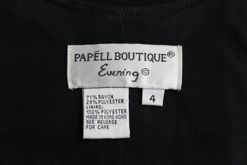 K&ouml;nnte beinhalten: Ein wei&szlig;es Etikett mit schwarzem Text, der "PAPELL BOUTIQUE&reg; Evening&reg;" lautet, und ein kleineres wei&szlig;es Etikett mit schwarzem Text, der "4" lautet. Unter dem gr&ouml;&szlig;eren Etikett befindet sich ein wei&szlig;es Etikett mit schwarzem Text, der die Stoffzusammensetzung auflistet: "71% Rayon 29% Polyester Futter: 100% Polyester Hergestellt in Hongkong Siehe R&uuml;ckseite f&uuml;r Pflegehinweise"