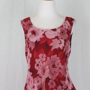 May include: A sleeveless dress with a red and pink floral print. The dress has a tiered skirt and a fitted bodice.