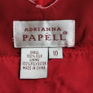 May include: White tag with black text that reads "Adrianna Papell" and "Shell 100% Silk Lining 100% Polyester Made in China". A smaller white tag with black text reads "10".