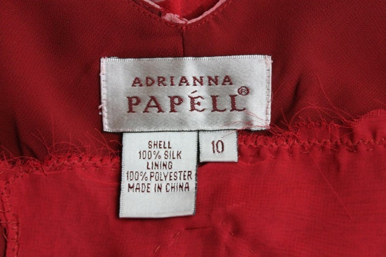 May include: White tag with black text that reads "Adrianna Papell" and "Shell 100% Silk Lining 100% Polyester Made in China". A smaller white tag with black text reads "10".