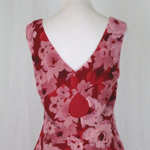 May include: A sleeveless red and pink floral print dress with a V-neckline and a tiered skirt.