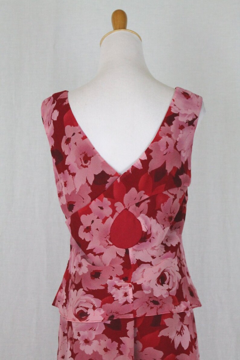May include: A sleeveless red and pink floral print dress with a V-neckline and a tiered skirt.
