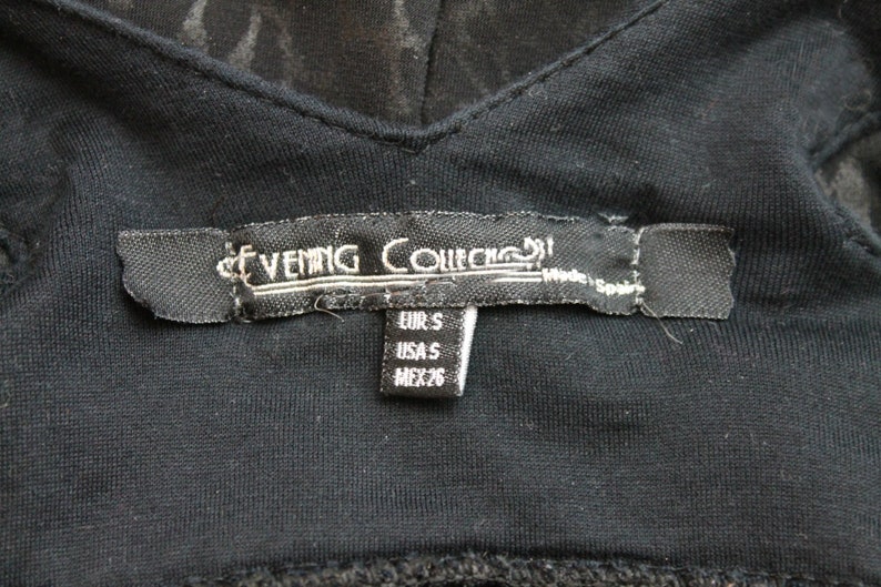 May include: Black clothing label with white text that reads "Evening Collection" and size information: EUR S, USA S, MEX 26.
