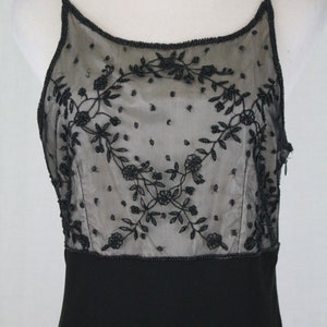 Pode incluir: Um vestido preto sem mangas com um corpete transparente de contas com um design floral. O corpete &eacute; forrado com um tecido preto.