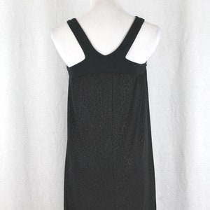 May include: Black sleeveless dress with a scoop neck and a leopard print pattern.