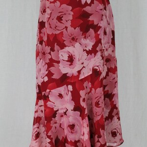May include: A red and pink floral skirt with a flowing hemline. The skirt is made of a lightweight fabric and has a casual, feminine style.