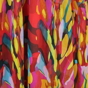 May include: Abstract floral print fabric in shades of red, yellow, pink, and blue. The fabric has a sheer, gauzy texture.