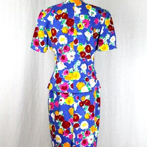 May include: A blue dress with a floral print featuring pink, red, yellow, and white flowers. The dress has a fitted bodice and a skirt with a slight A-line shape.
