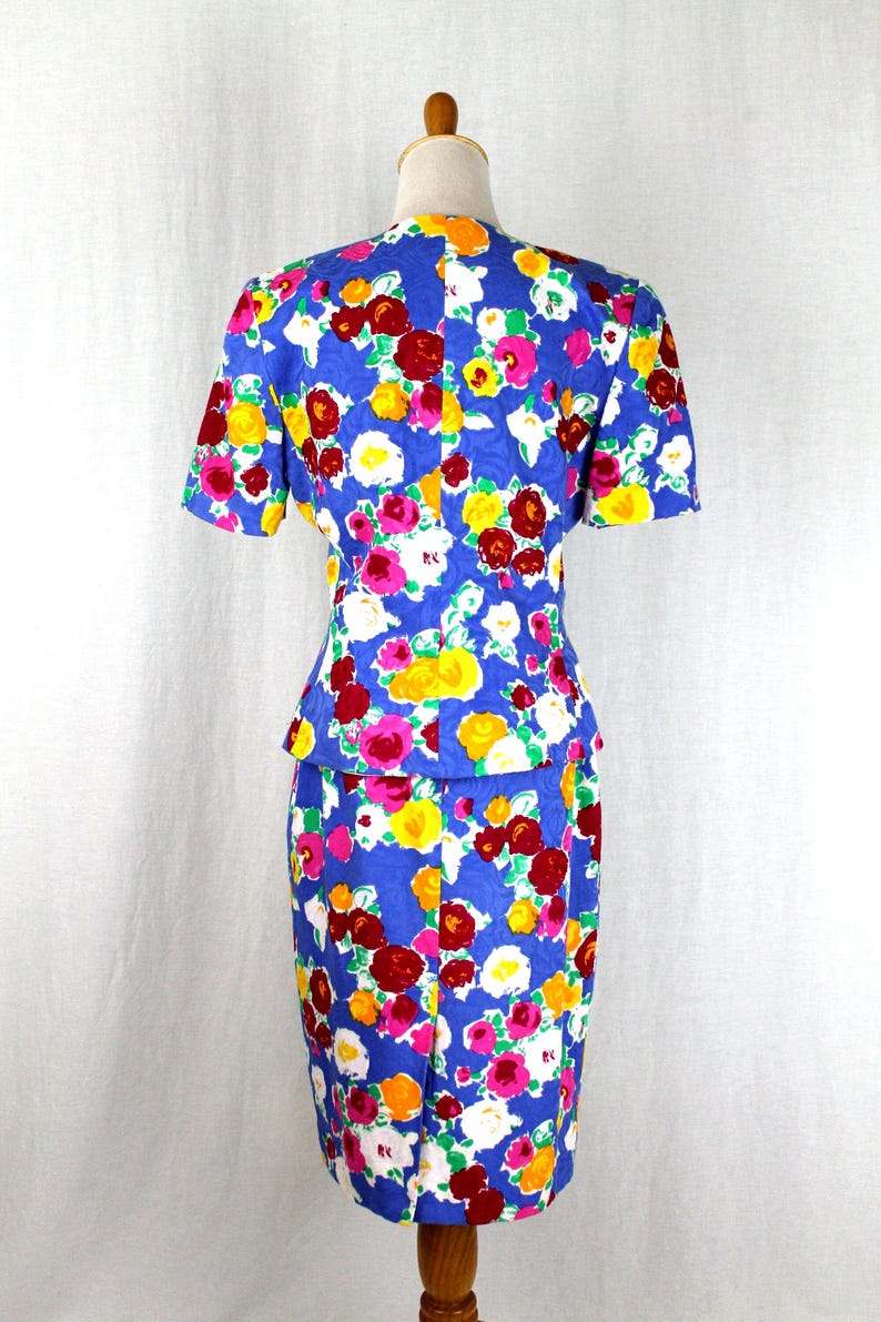 May include: A blue dress with a floral print featuring pink, red, yellow, and white flowers. The dress has a fitted bodice and a skirt with a slight A-line shape.