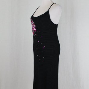 May include: A black knit midi dress with a pink and clear rhinestone embellishment on the bodice.