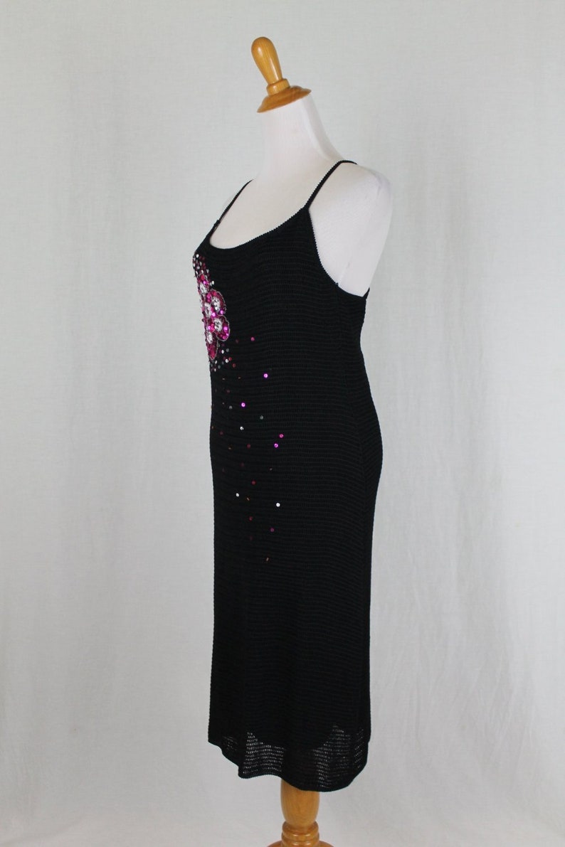 May include: A black knit midi dress with a pink and clear rhinestone embellishment on the bodice.
