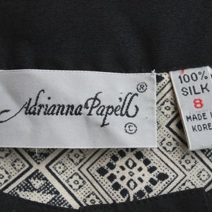 May include: A white tag with black text that reads "Adrianna Papell" and a size 8 tag that reads "100% Silk Made in Korea".