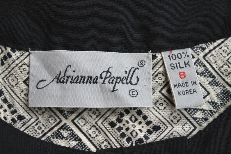 May include: A white tag with black text that reads "Adrianna Papell" and a size 8 tag that reads "100% Silk Made in Korea".