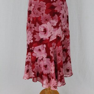 May include: A red and pink floral skirt with a ruffled hem. The skirt is made of a lightweight fabric and has a flowing silhouette.