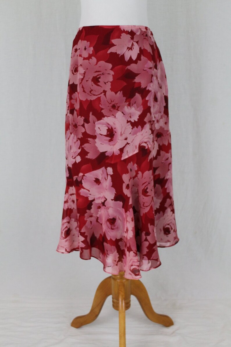May include: A red and pink floral skirt with a ruffled hem. The skirt is made of a lightweight fabric and has a flowing silhouette.