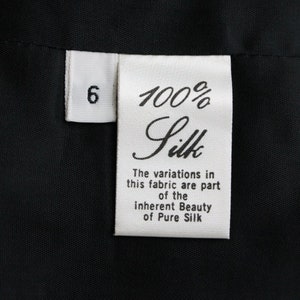 May include: White fabric tag with black text that reads "6 100% Silk The variations in this fabric are part of the inherent Beauty of Pure Silk"