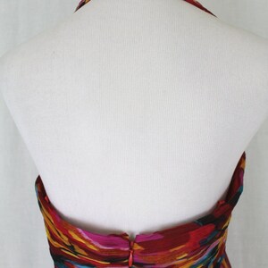 May include: Back view of a halter-style dress with a colourful abstract print. The dress has a zip closure at the back and a beaded neckline.