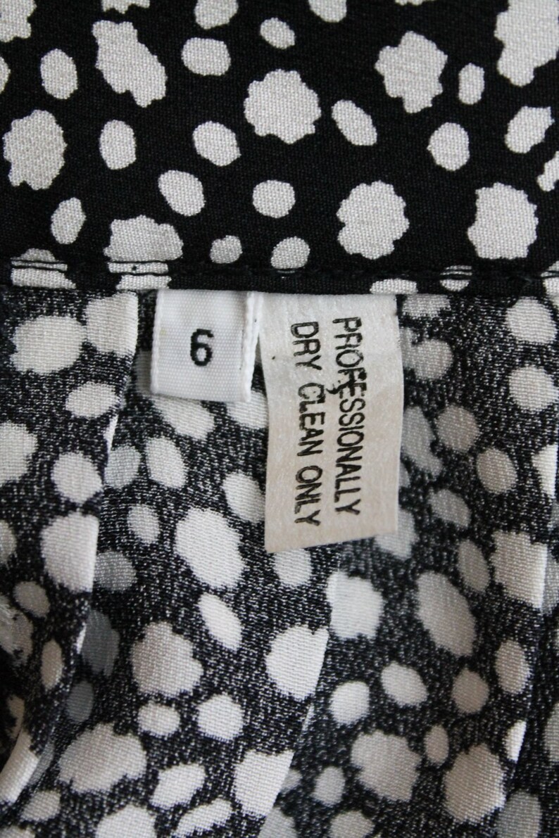 May include: White tag with black text that reads "Professionally Dry Clean Only" and a white tag with black text that reads "6". The tags are on a black and white fabric with a polka dot pattern.